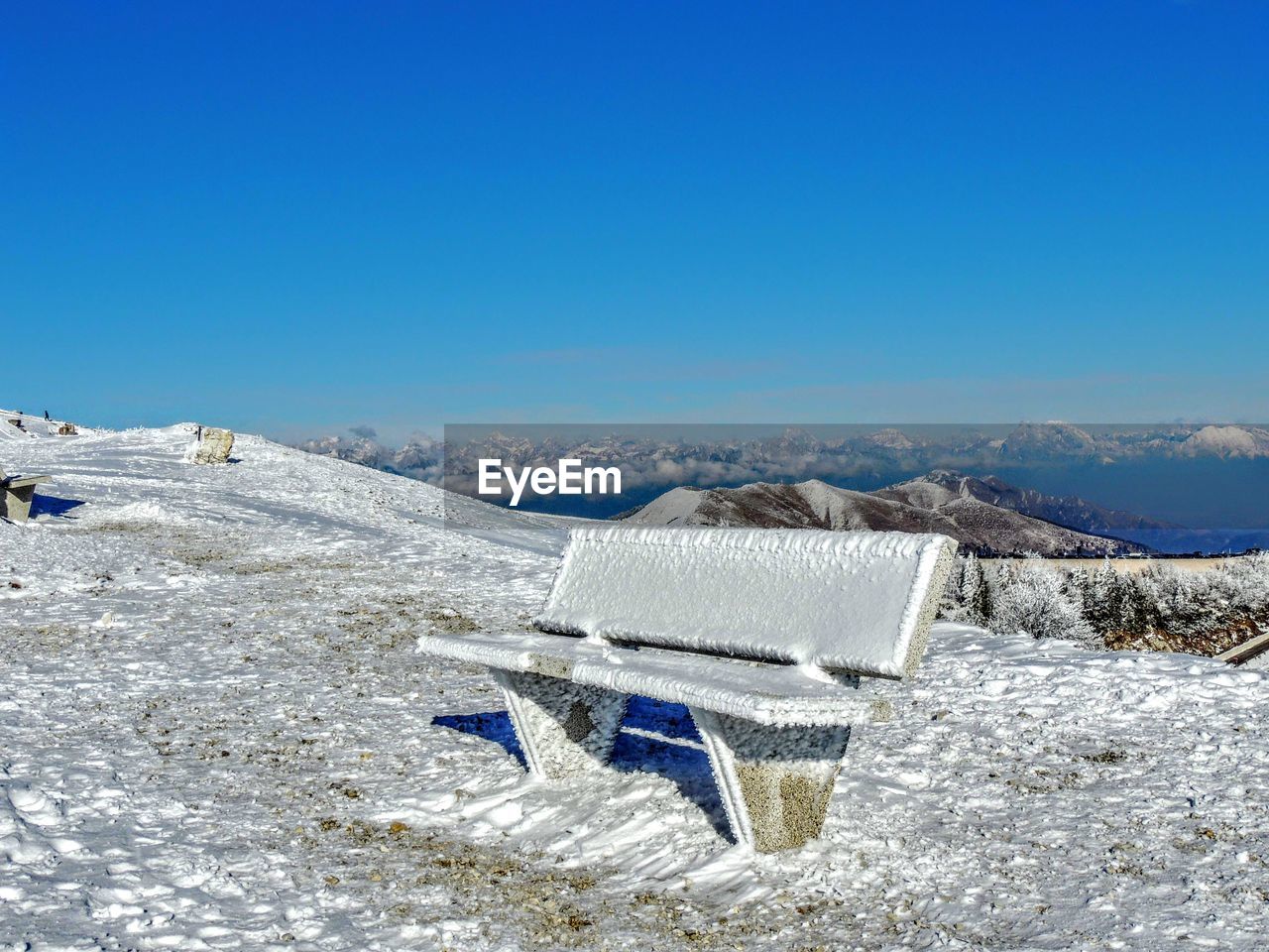 Snow covered land against clear blue sky