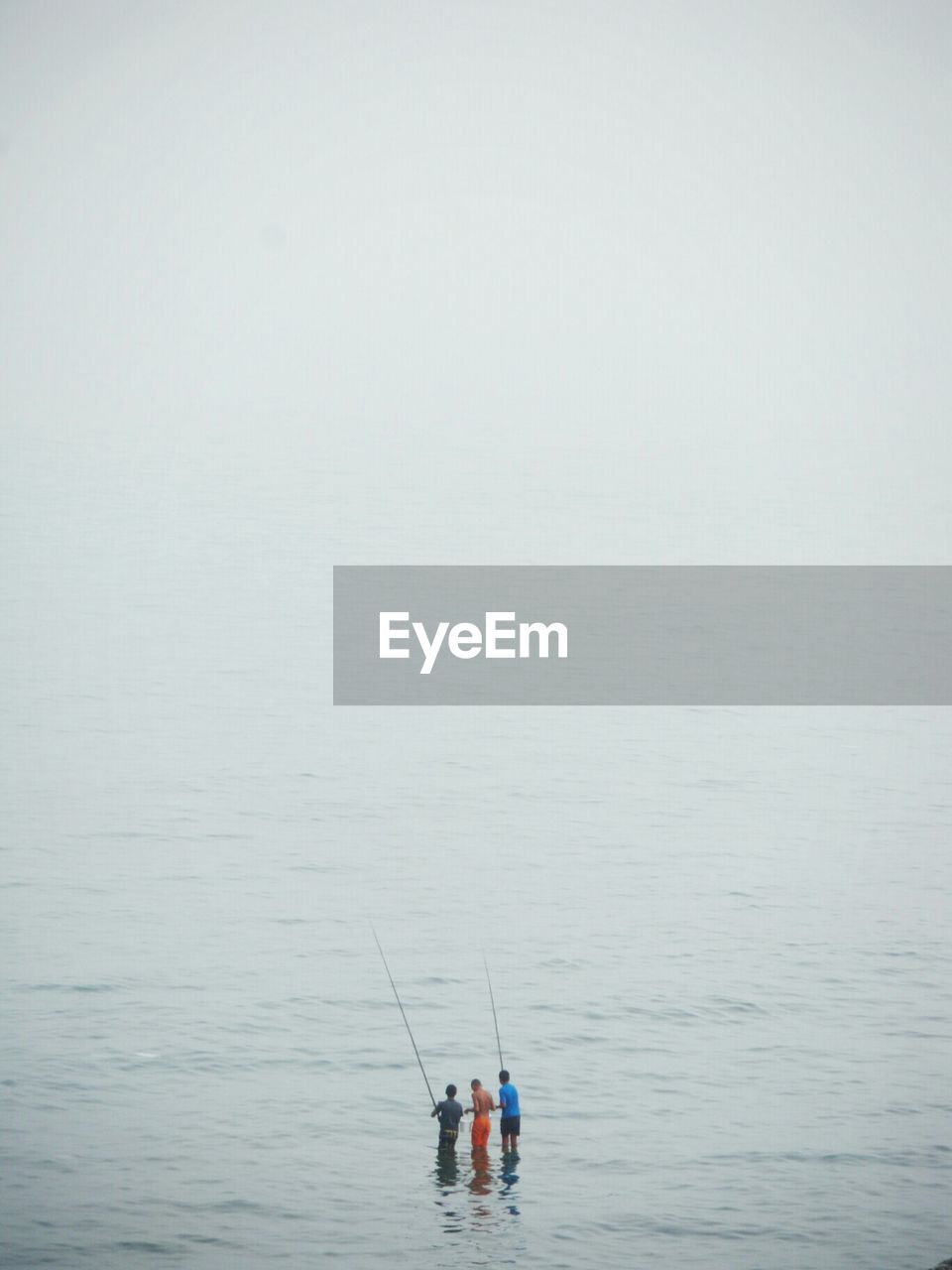 People fishing in sea against sky