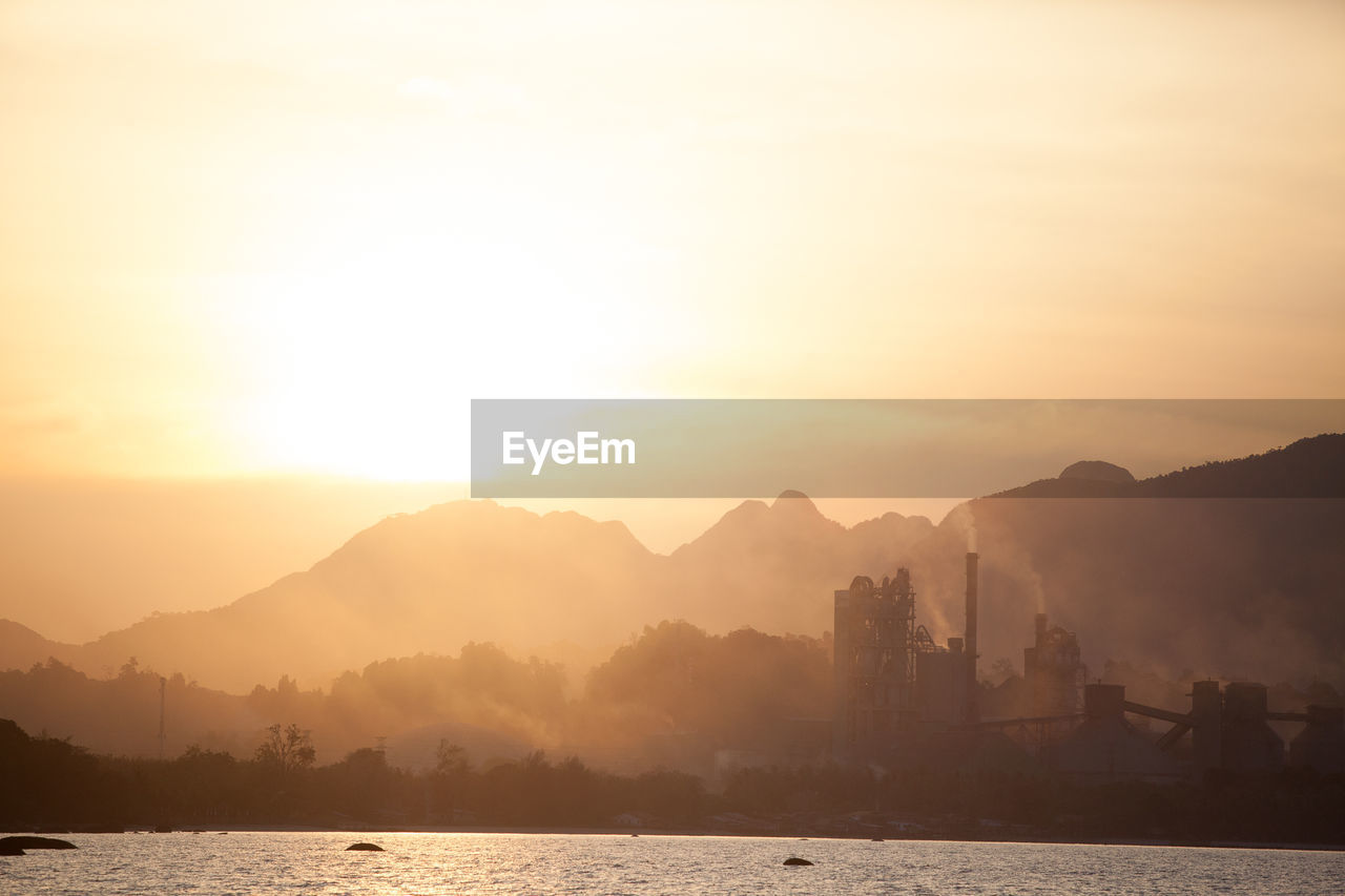 Scenic view of sea and silhouette mountains against sky during sunset