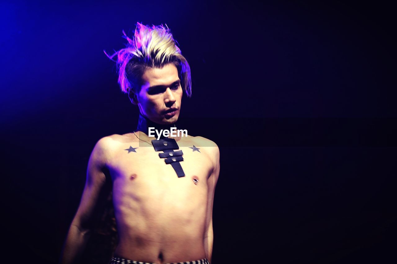 YOUNG MAN WEARING MASK AGAINST BLACK BACKGROUND