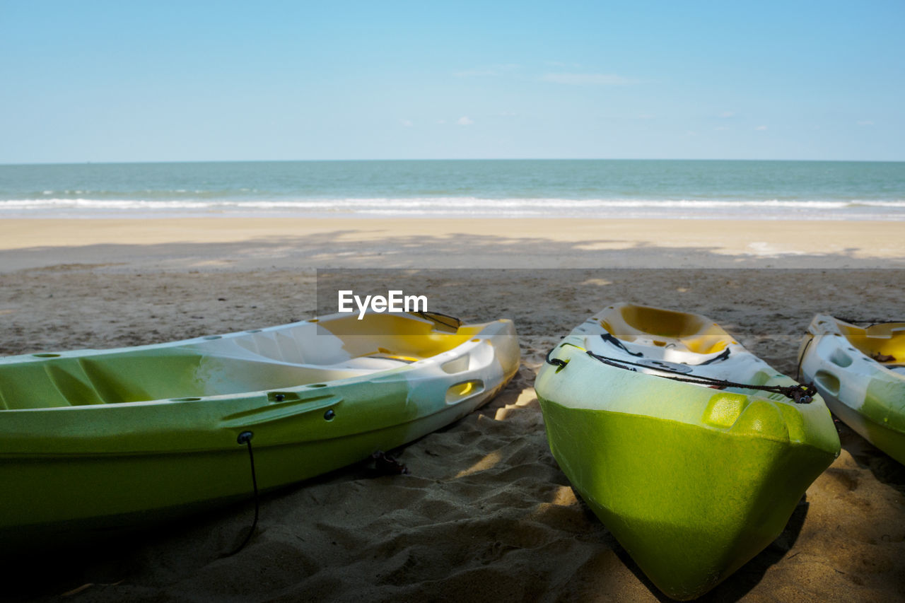 A green kayak parked in the sand by the tropical sea 