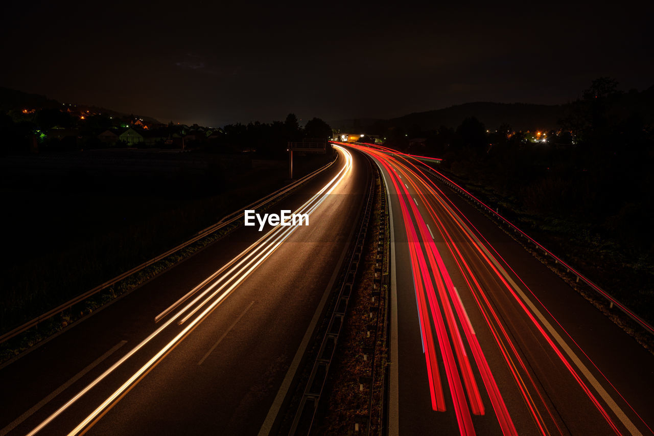 Many red car light trails on a road glowing