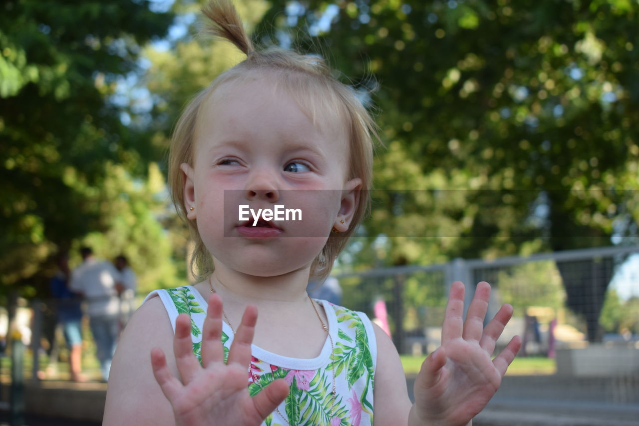 Close-up of girl making face against trees at park