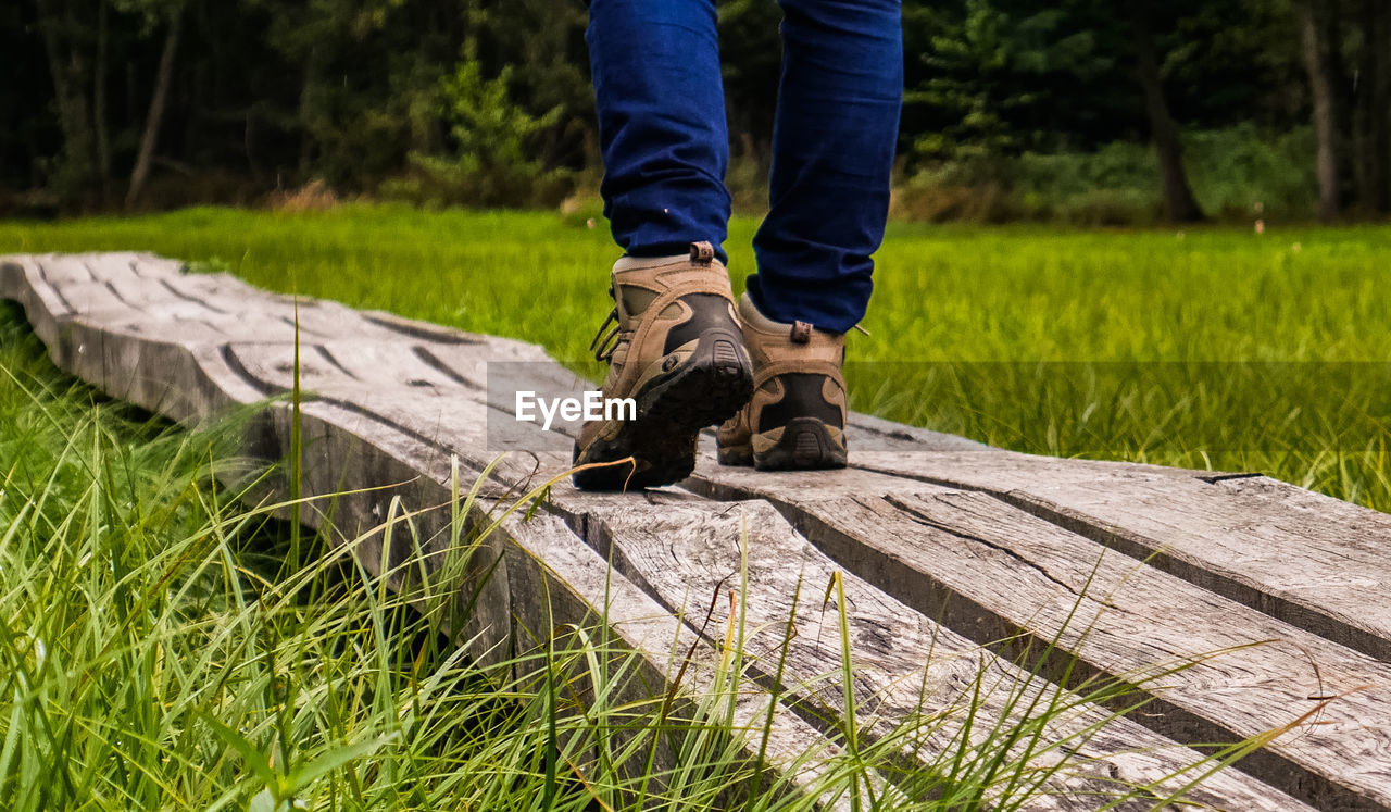 LOW SECTION OF PERSON STANDING ON FIELD BY LAND