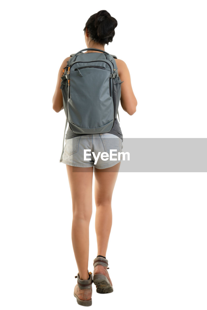 Rear view of female tourist with backpack against white background