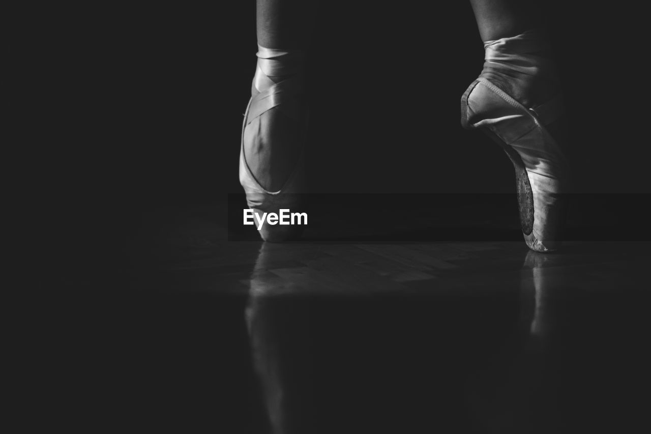 Low section of ballerina balancing on toe against black background