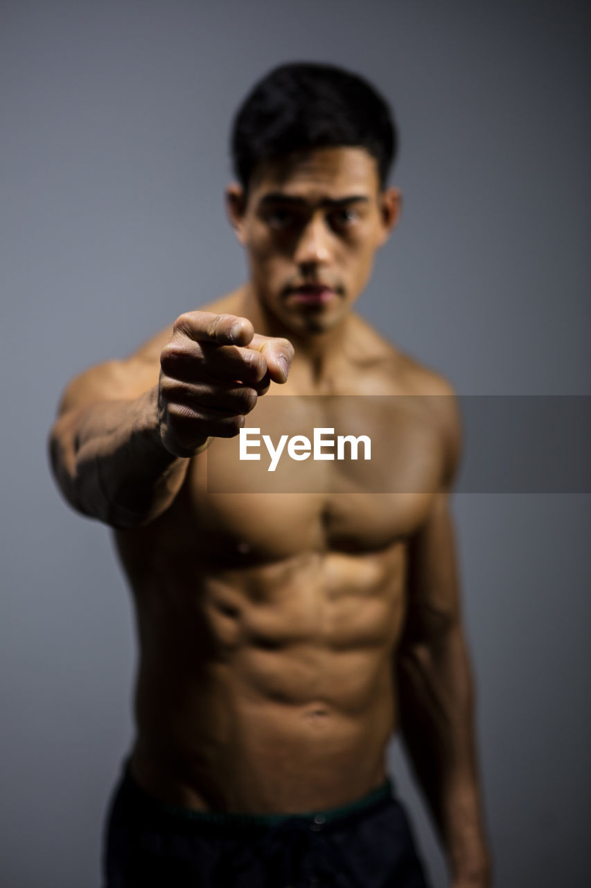 Shirtless muscular man standing against gray background