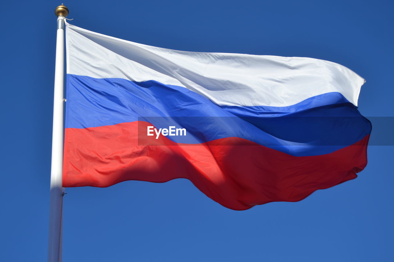 Low angle view of flag against blue sky