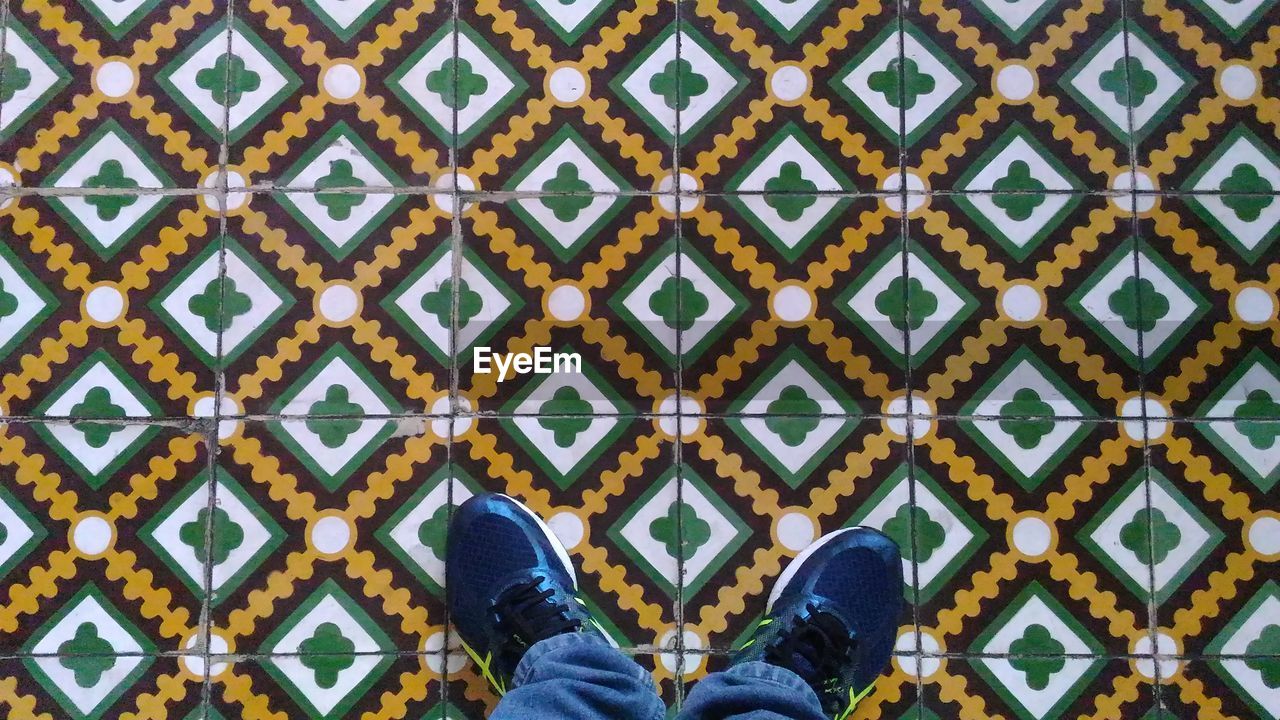 Low section of man standing on tiled floor