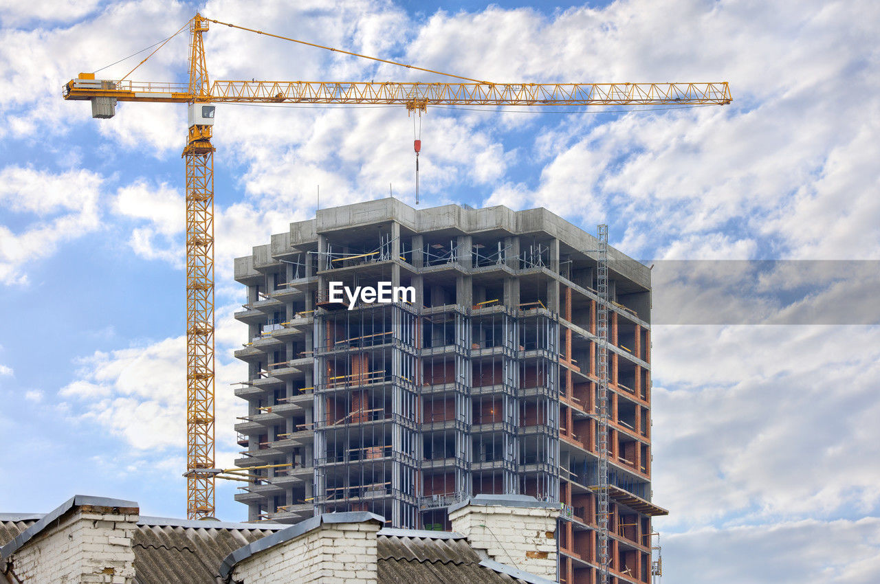 A tower crane works on the construction site of a modern multi-storey residential building.