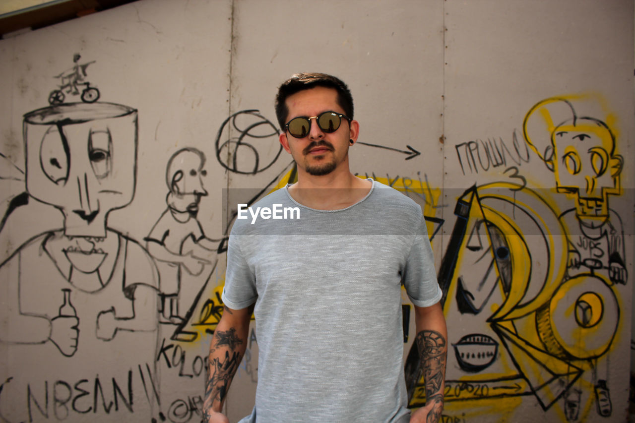 Young man standing against graffiti wall