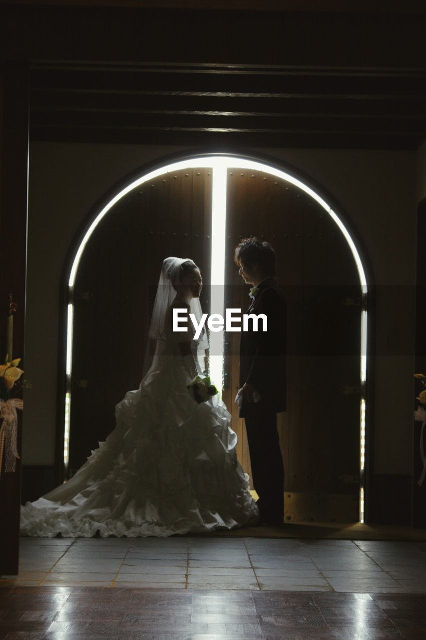 Side view of newlywed couple standing at entrance in church