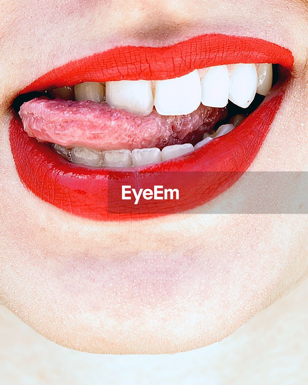 Cropped image of woman with red lipstick sticking out tongue