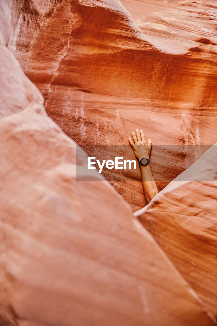 Hand with fitness watch against slot canyon wall in escalante, utah.