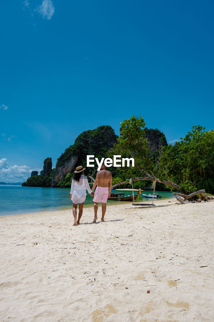 rear view of people at beach against blue sky