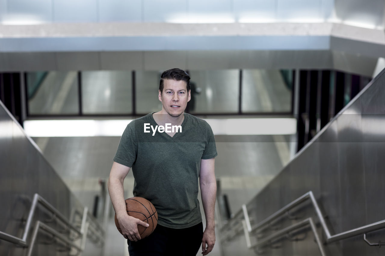 High angle portrait of young man with basketball moving up on steps