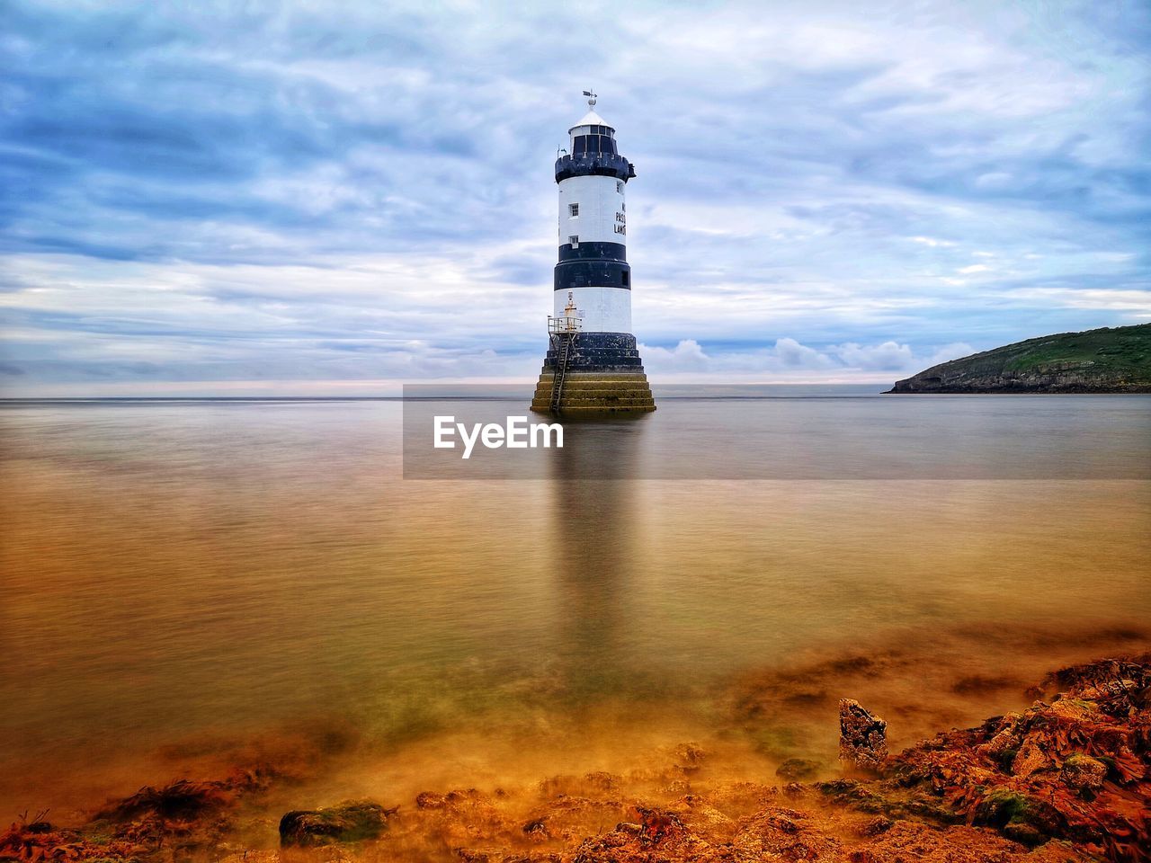 lighthouse, guidance, water, sea, sky, tower, architecture, beach, built structure, land, building exterior, building, security, nature, protection, reflection, cloud, coast, coastline, scenics - nature, ocean, travel destinations, no people, tranquility, travel, horizon, beauty in nature, outdoors, water's edge, landscape, tranquil scene, environment, dusk, shore, day, non-urban scene, sand, illuminated, evening, idyllic, sunset, nautical vessel