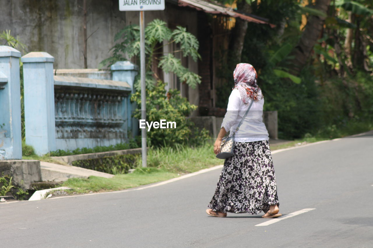 Rear view of woman walking on road