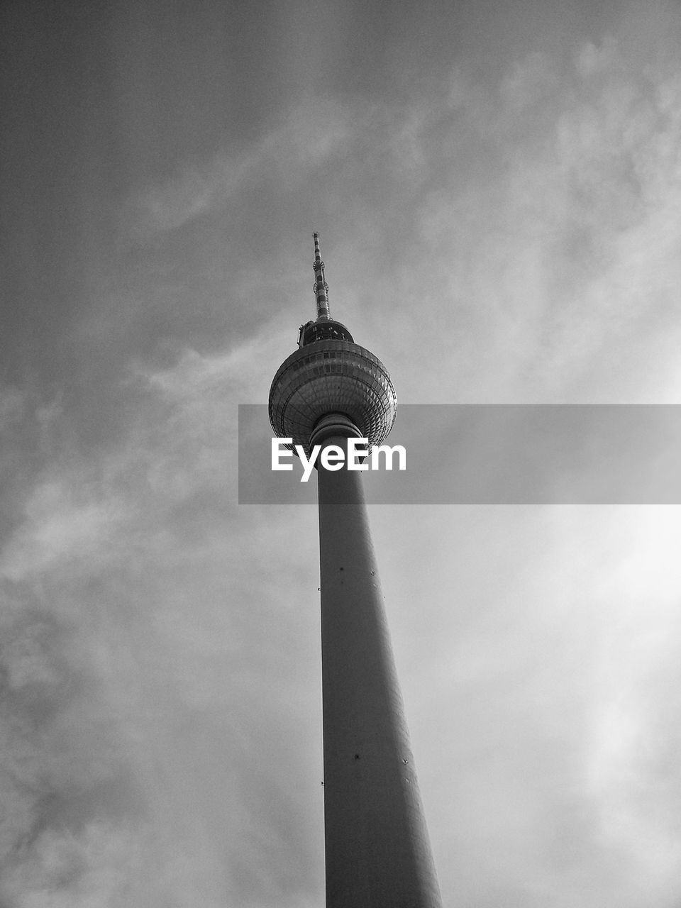 Low angle view of communications tower against cloudy sky