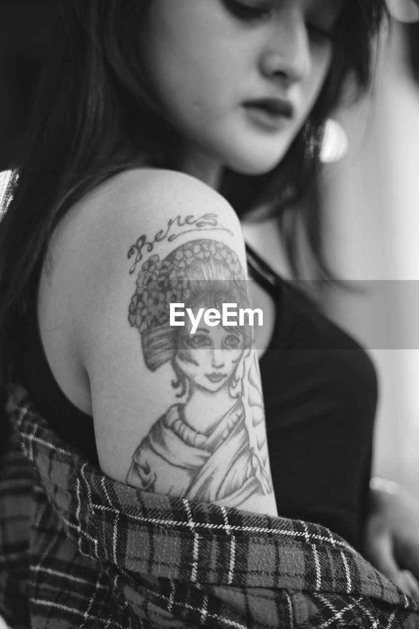 Close-up of young woman showing tattoo