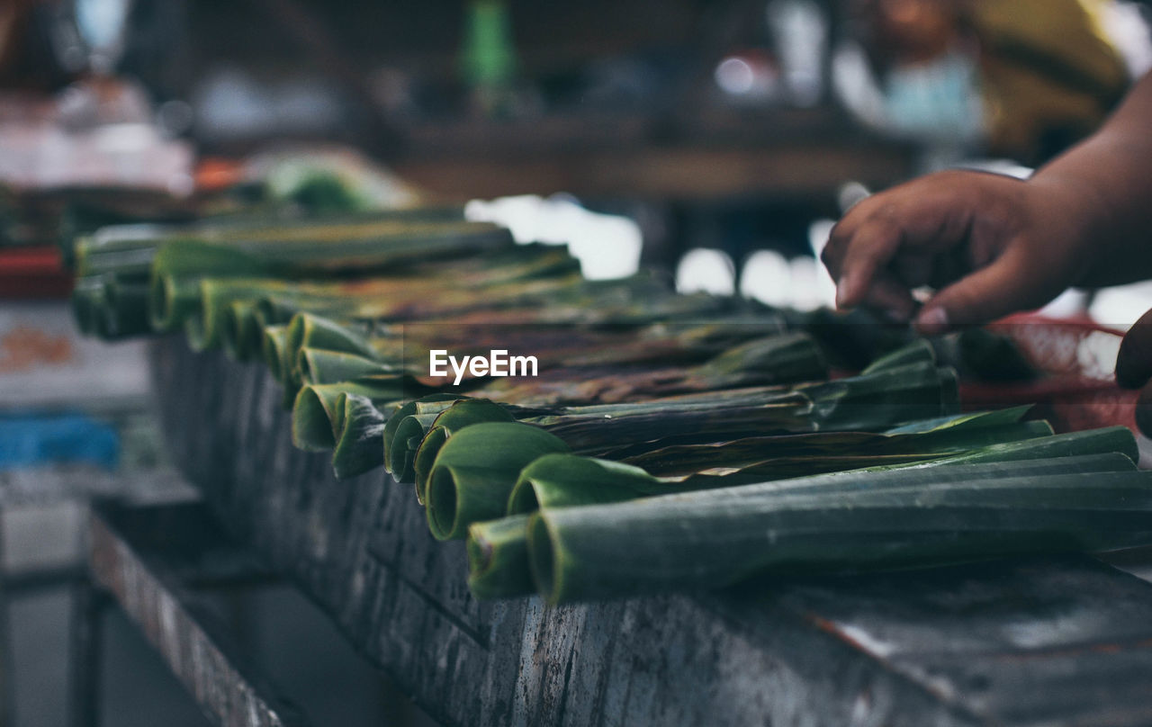 Cropped image of hand on selling leaves at market