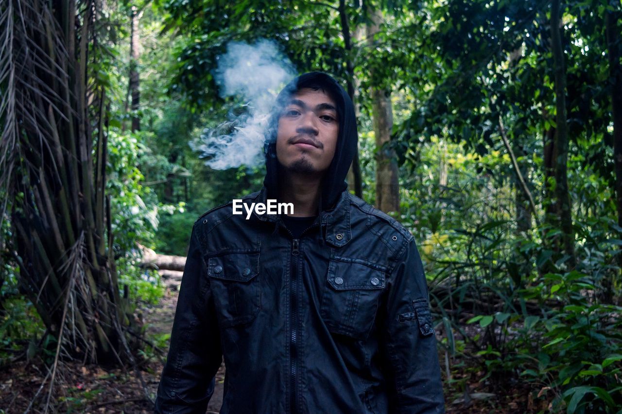 Portrait of man exhaling smoke in forest