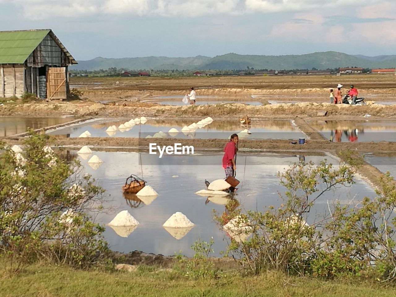 MAN WORKING ON FIELD BY MOUNTAIN AGAINST SKY