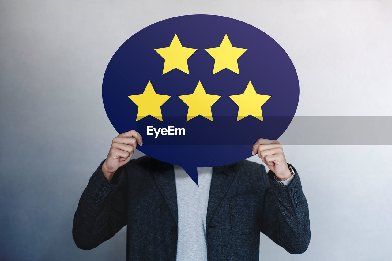 Man covering face with placard against gray background