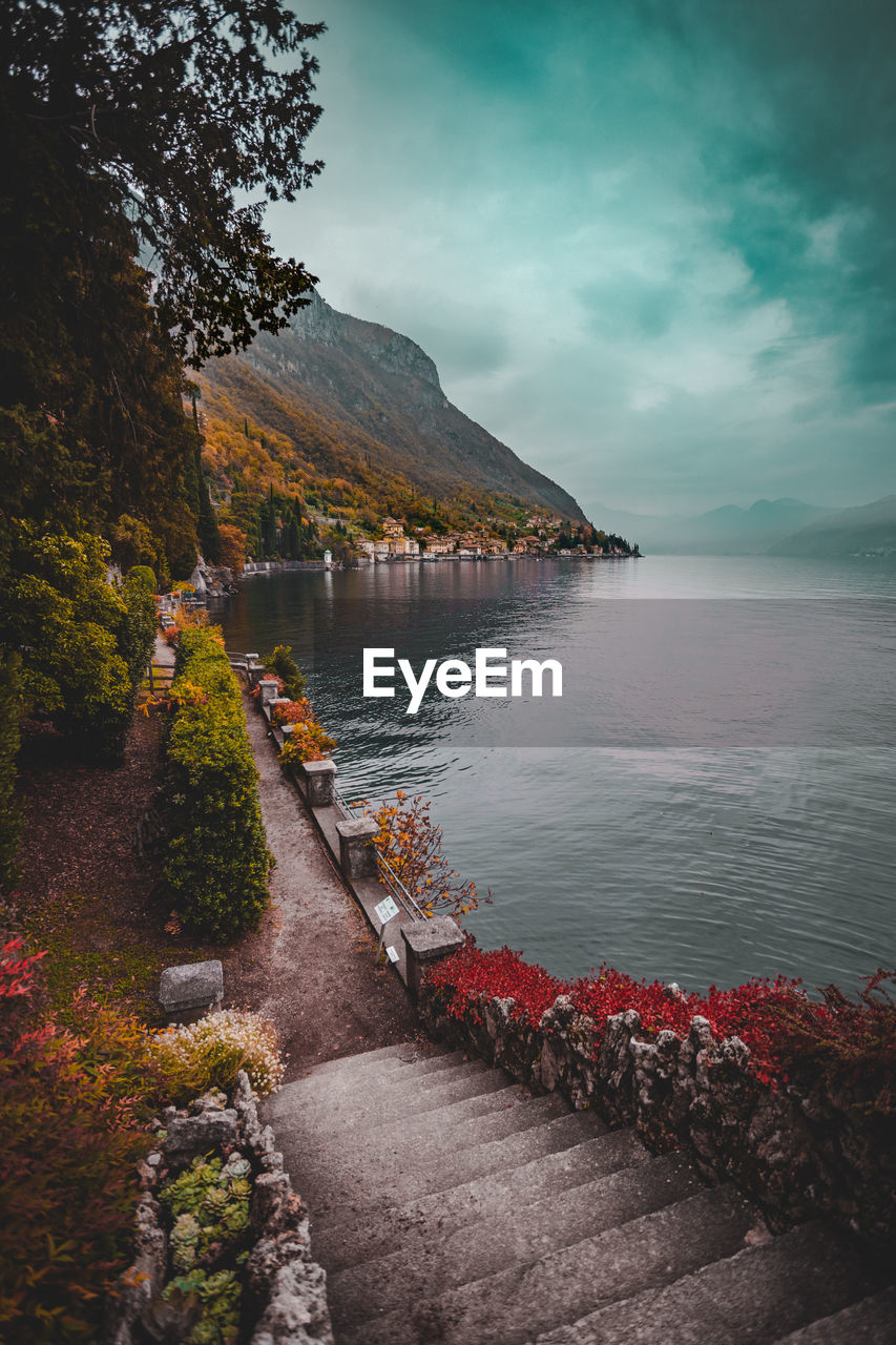 Garden next to a large body of water with mountains in the background during an overcast day