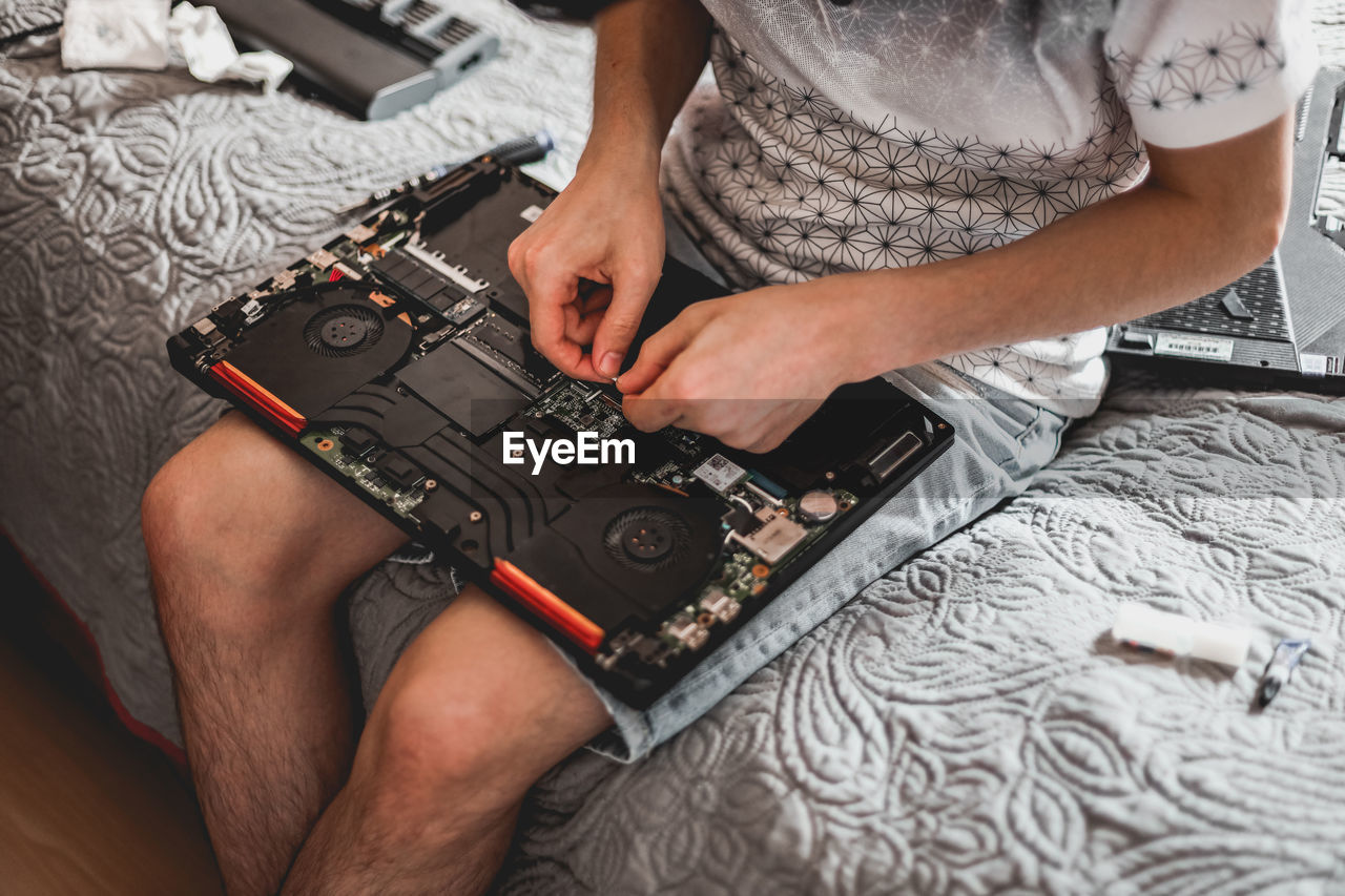 A young man is changing the thermal paste on a laptop.