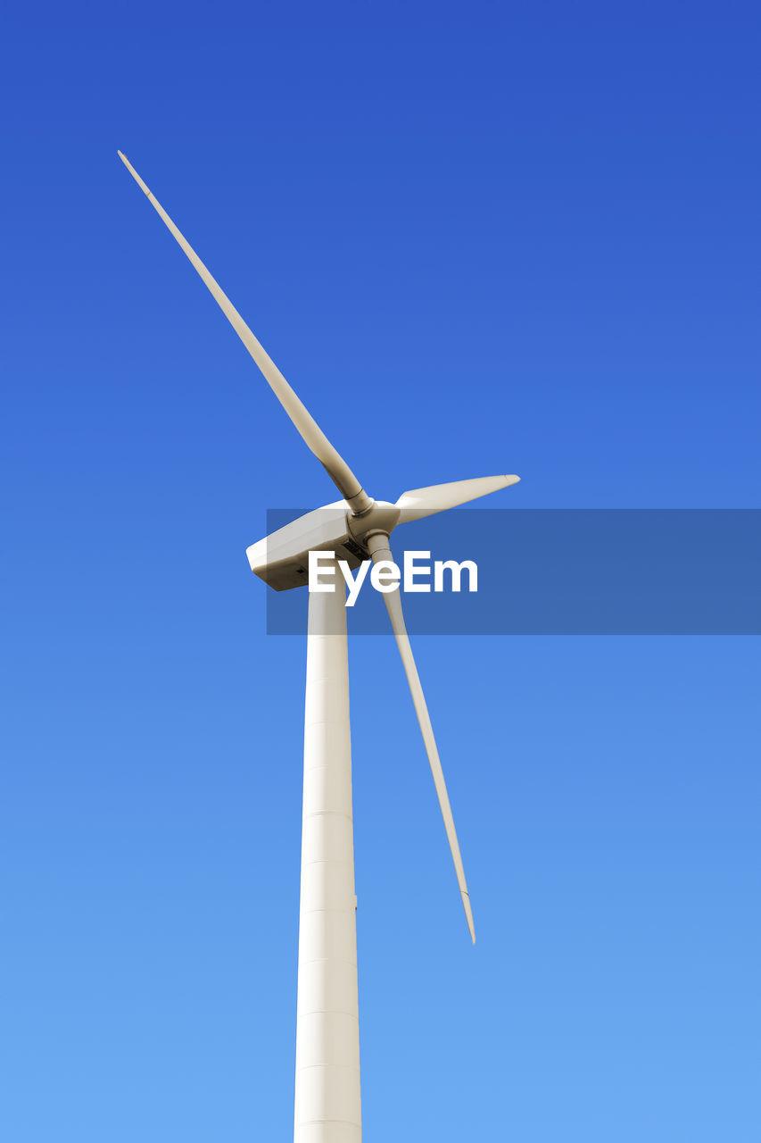 Low angle view of windmill against clear blue sky