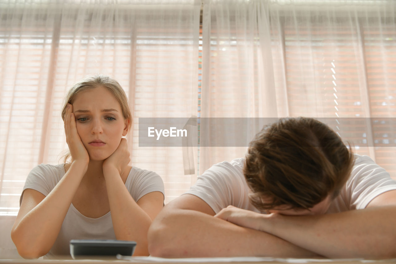 Young woman using mobile phone while lying on bed at home