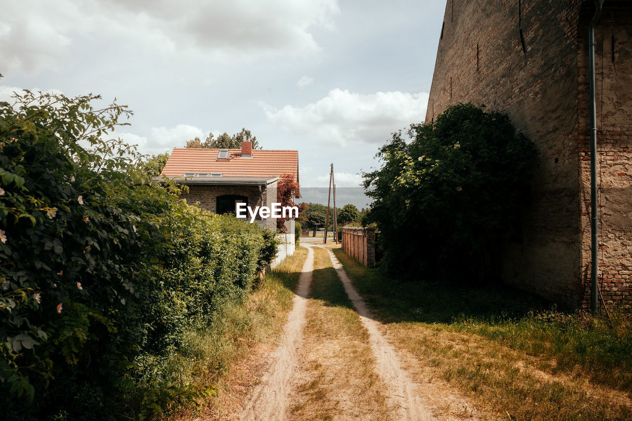 Footpath amidst village against sky