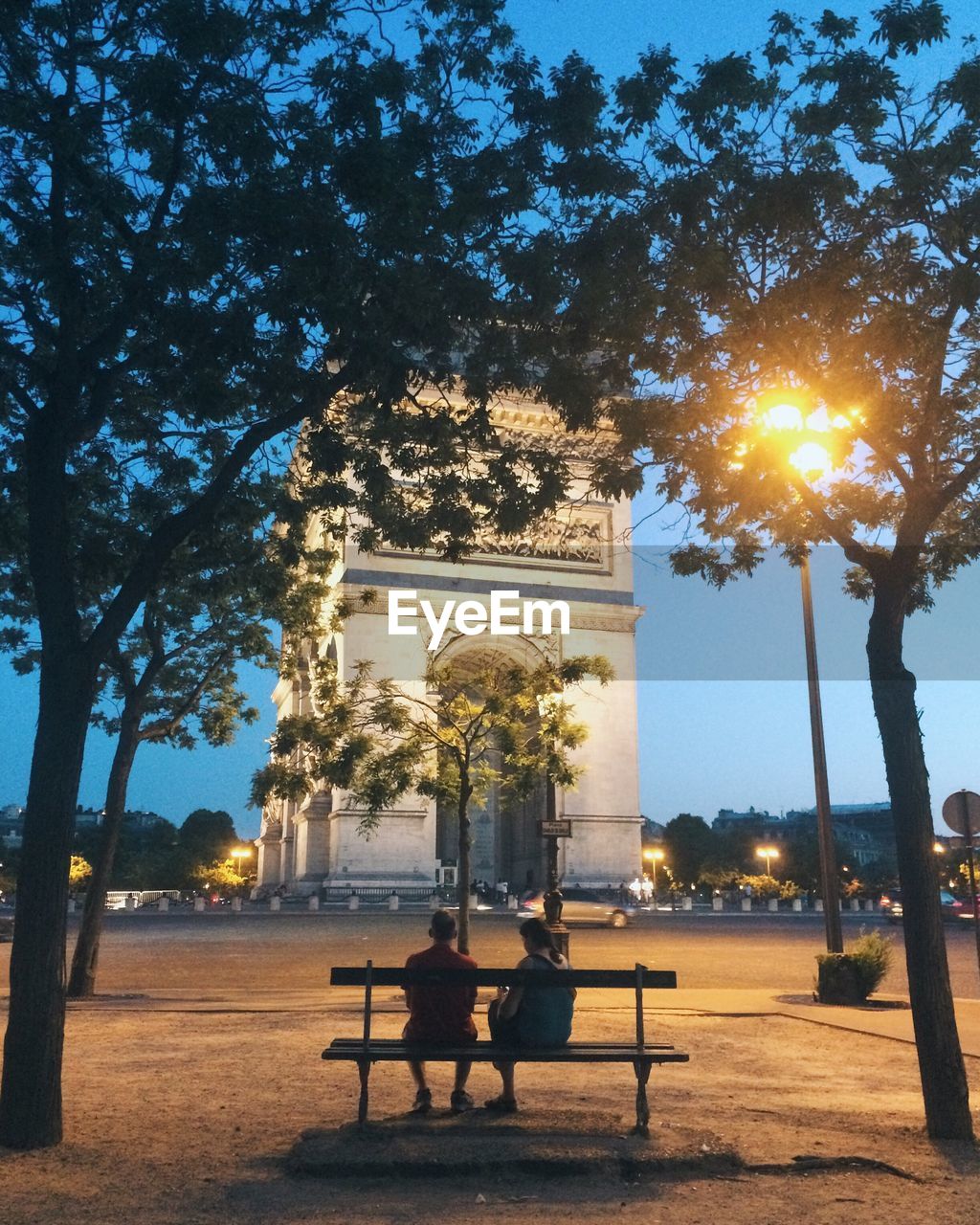 PEOPLE SITTING AT PARK AGAINST TREES