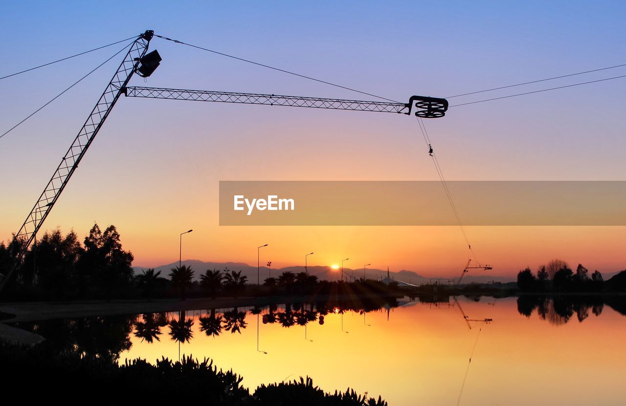 Scenic view of lake with trees and orange sky reflection at sunset