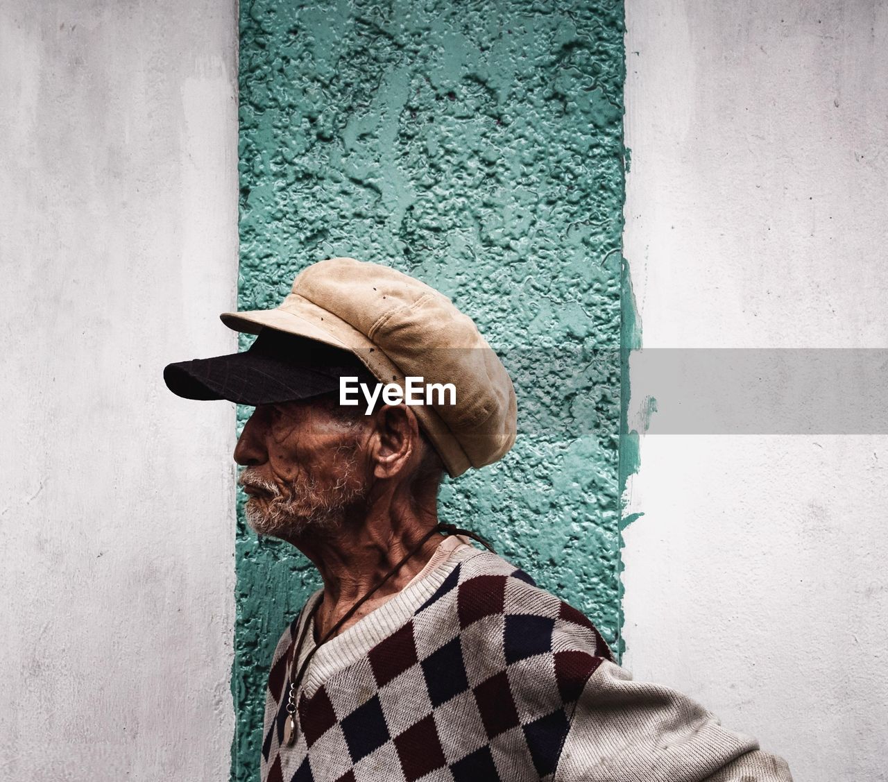 Side view of senior man standing against wall