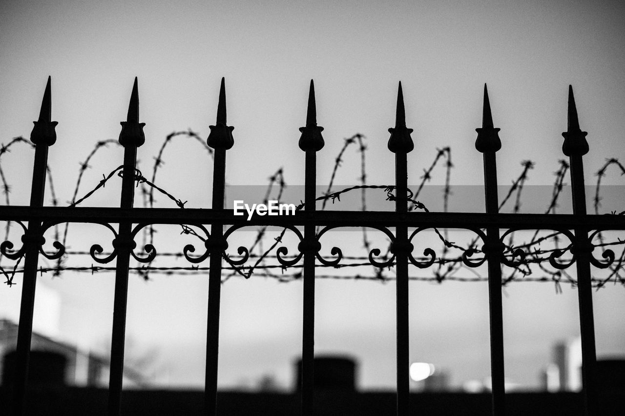 Low angle view of silhouette fence against sky