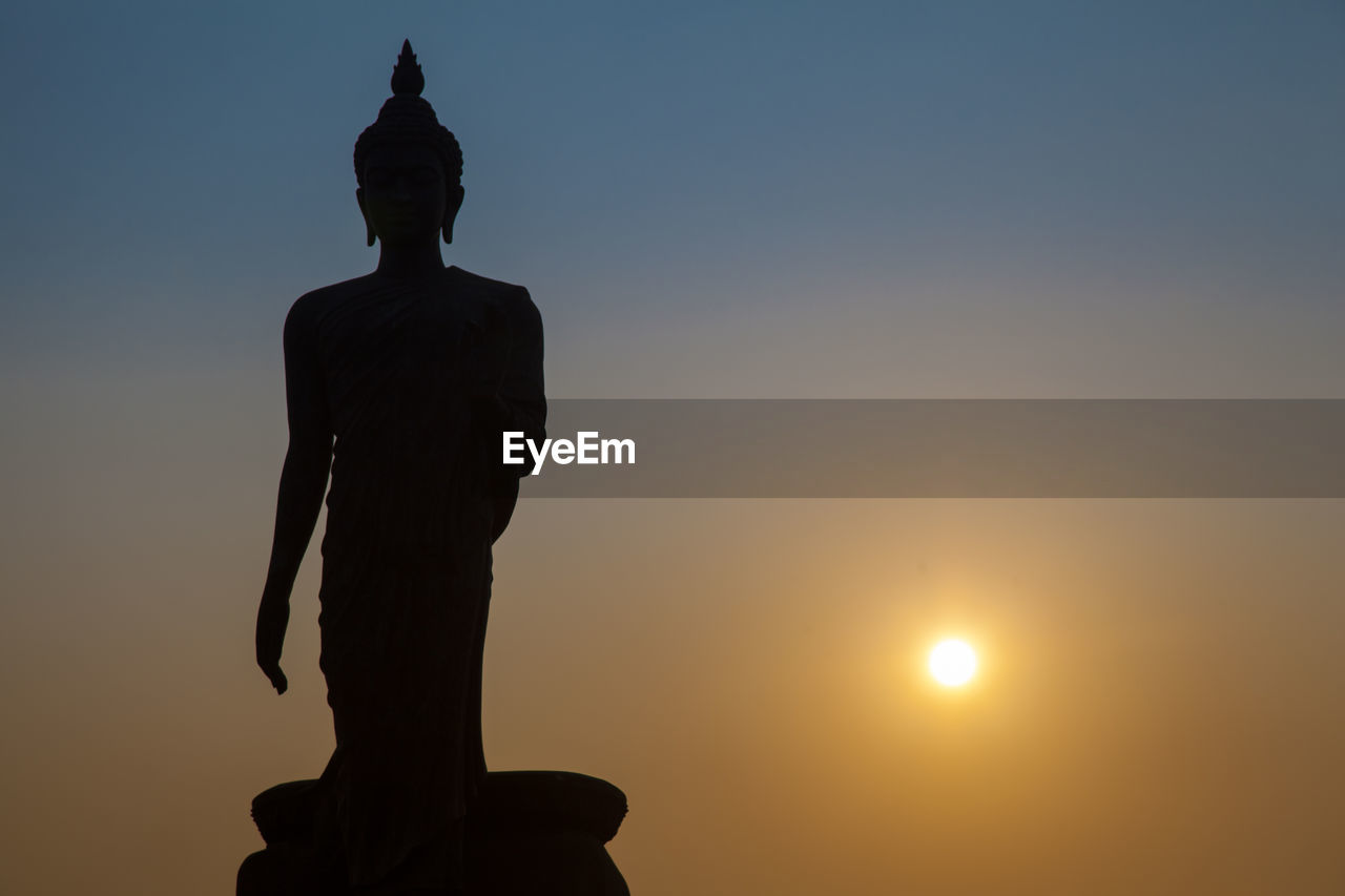 Low angle view of silhouette buddha statue against sky during sunset