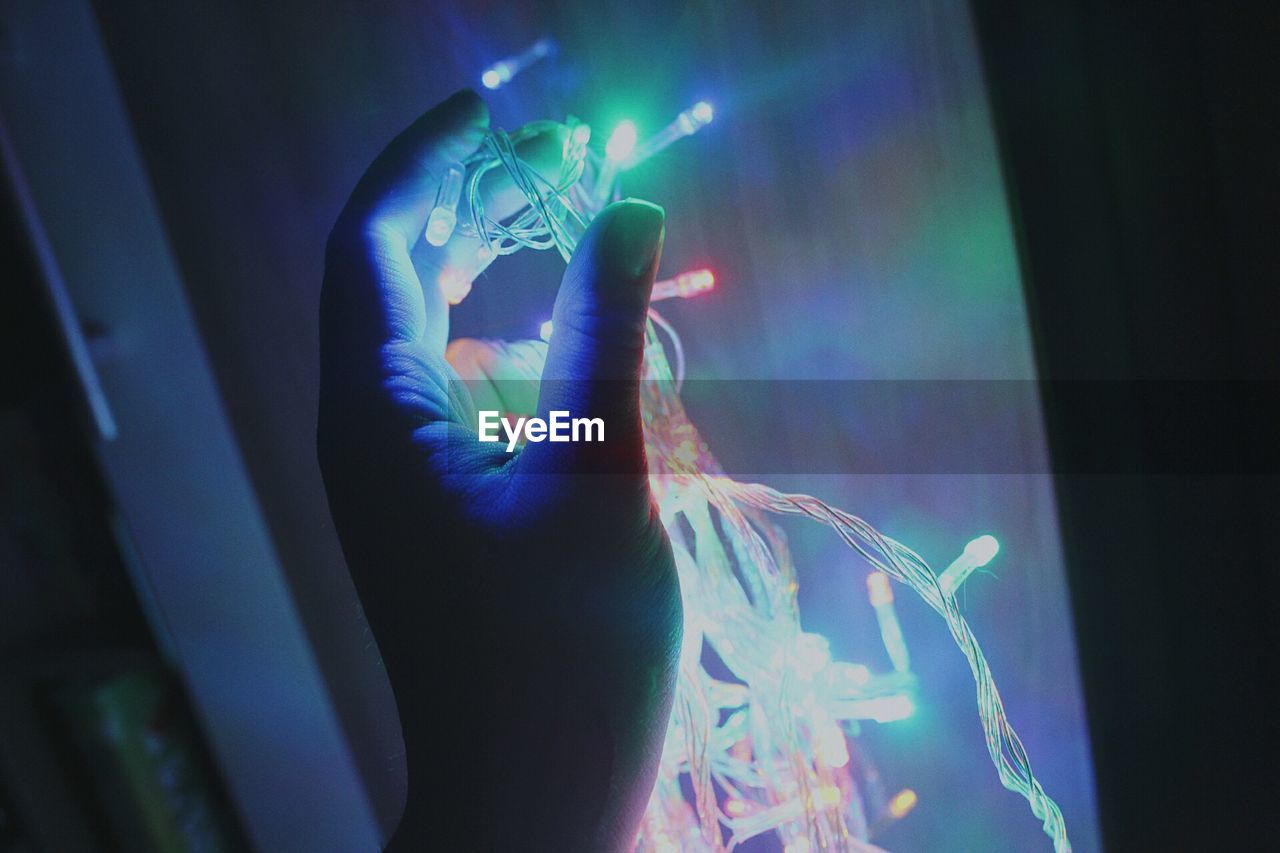 Close-up of hand holding illuminated string light 