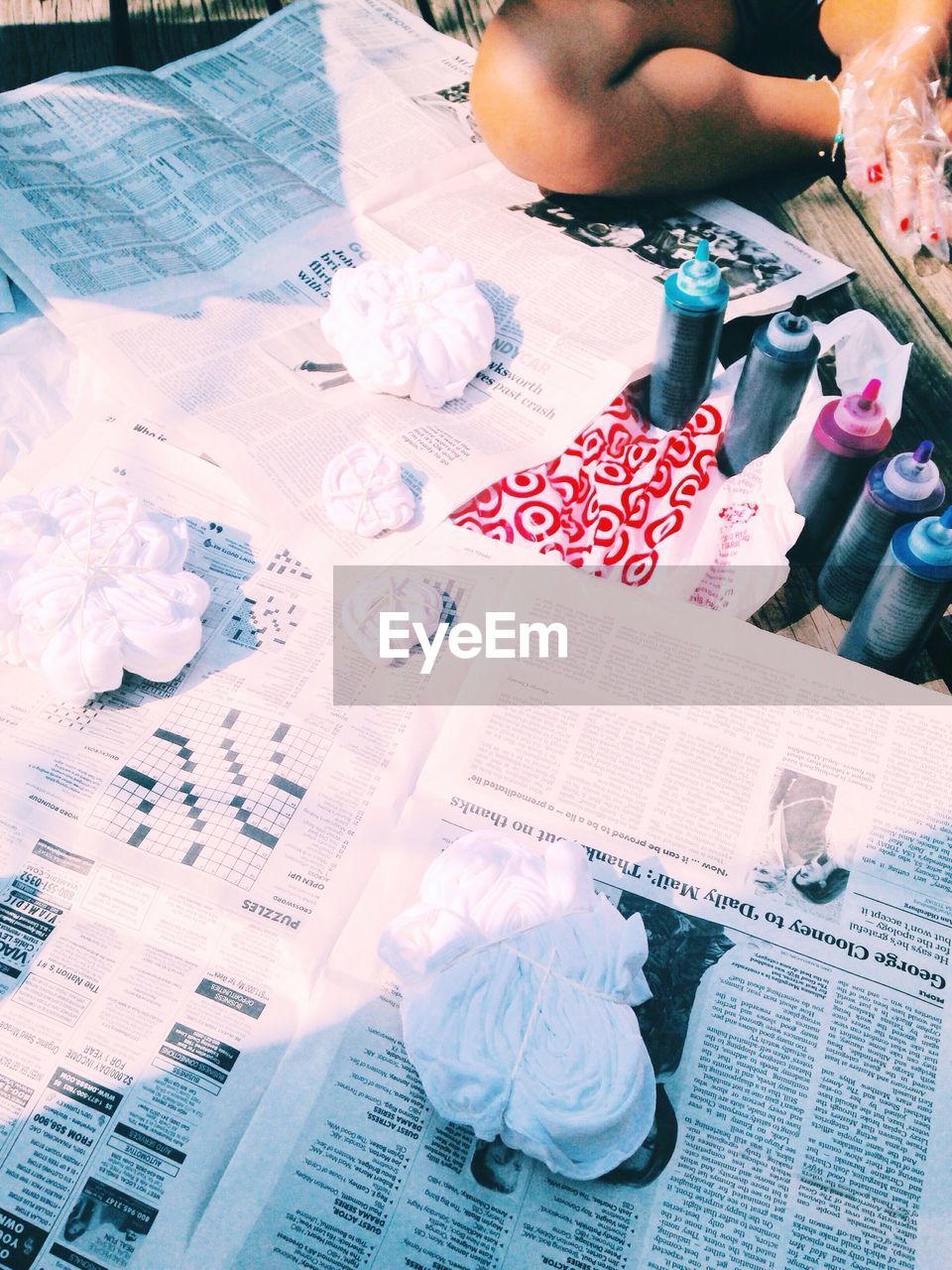 Cropped image of woman tie-dyeing clothes on newspaper
