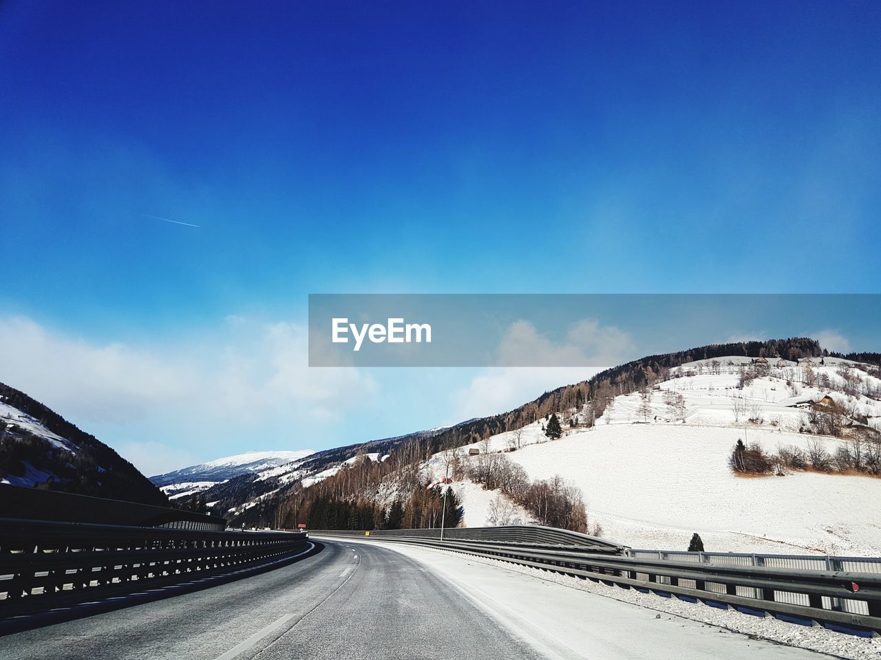 Road by mountain against sky during winter