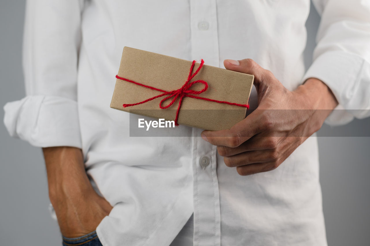 MIDSECTION OF MAN HOLDING PAPER WITH BOX