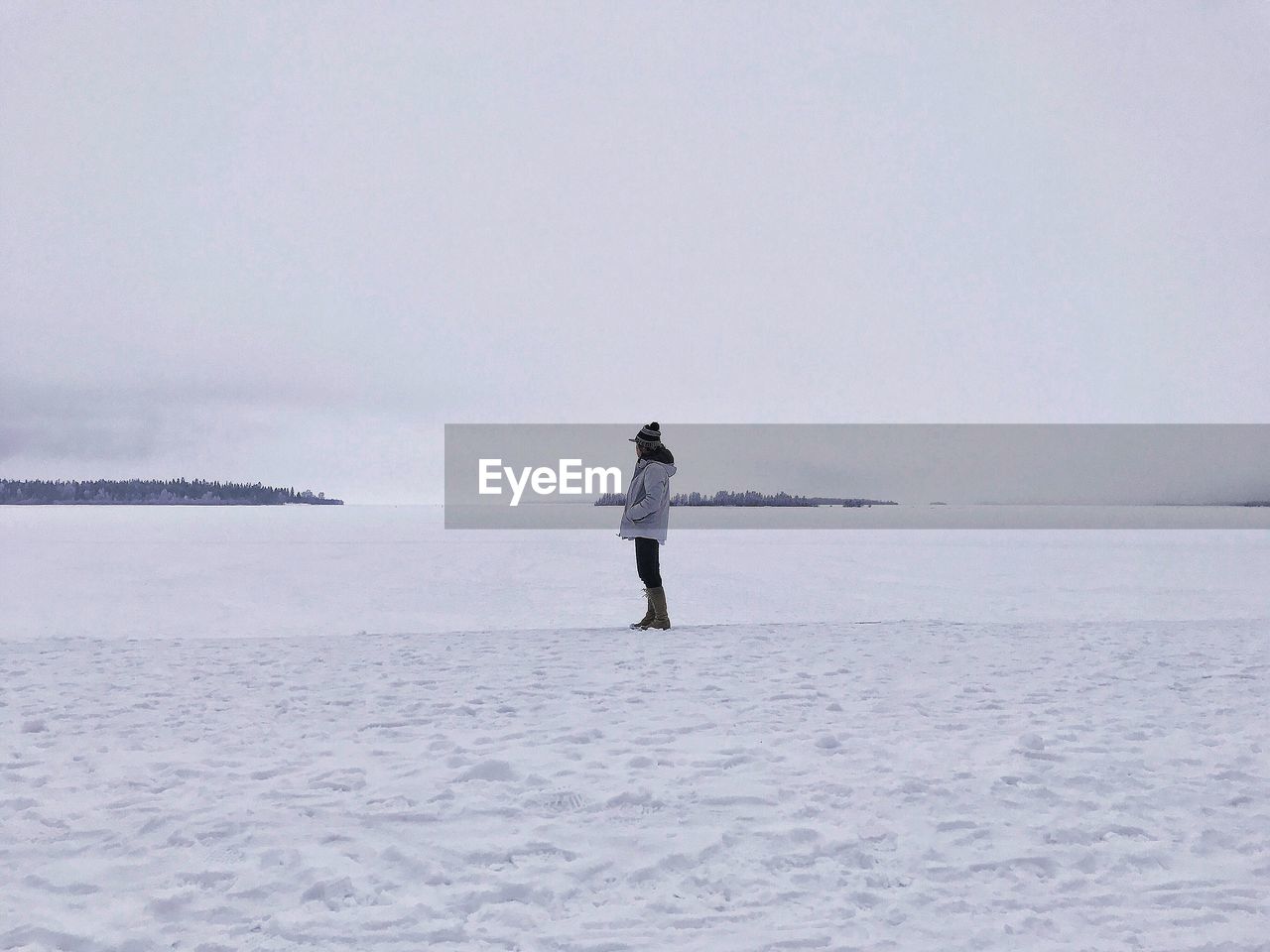 Side view of man standing on snow covered field against sky