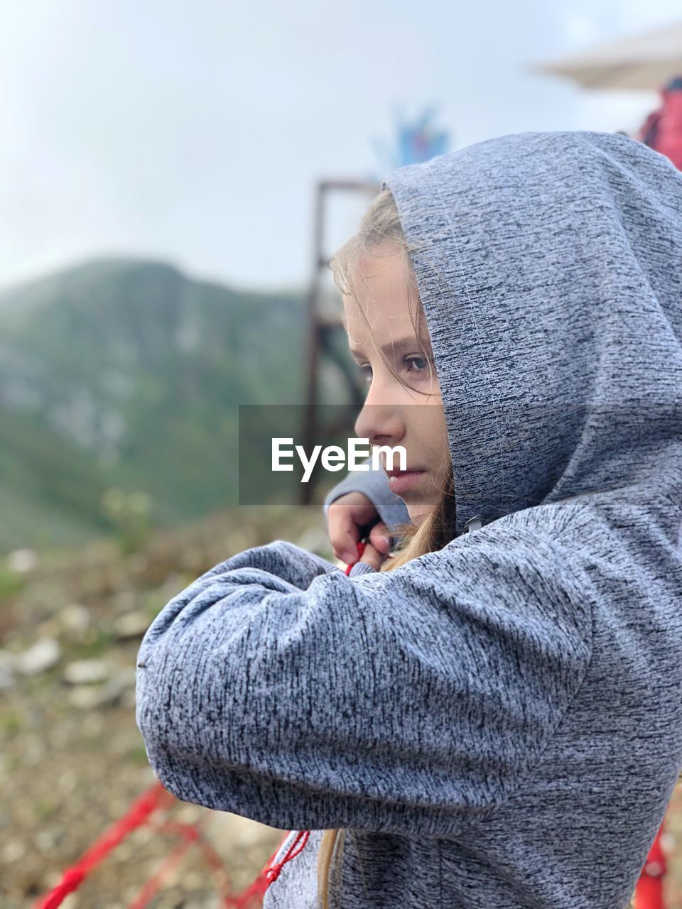 Girl wearing hood while looking at mountains