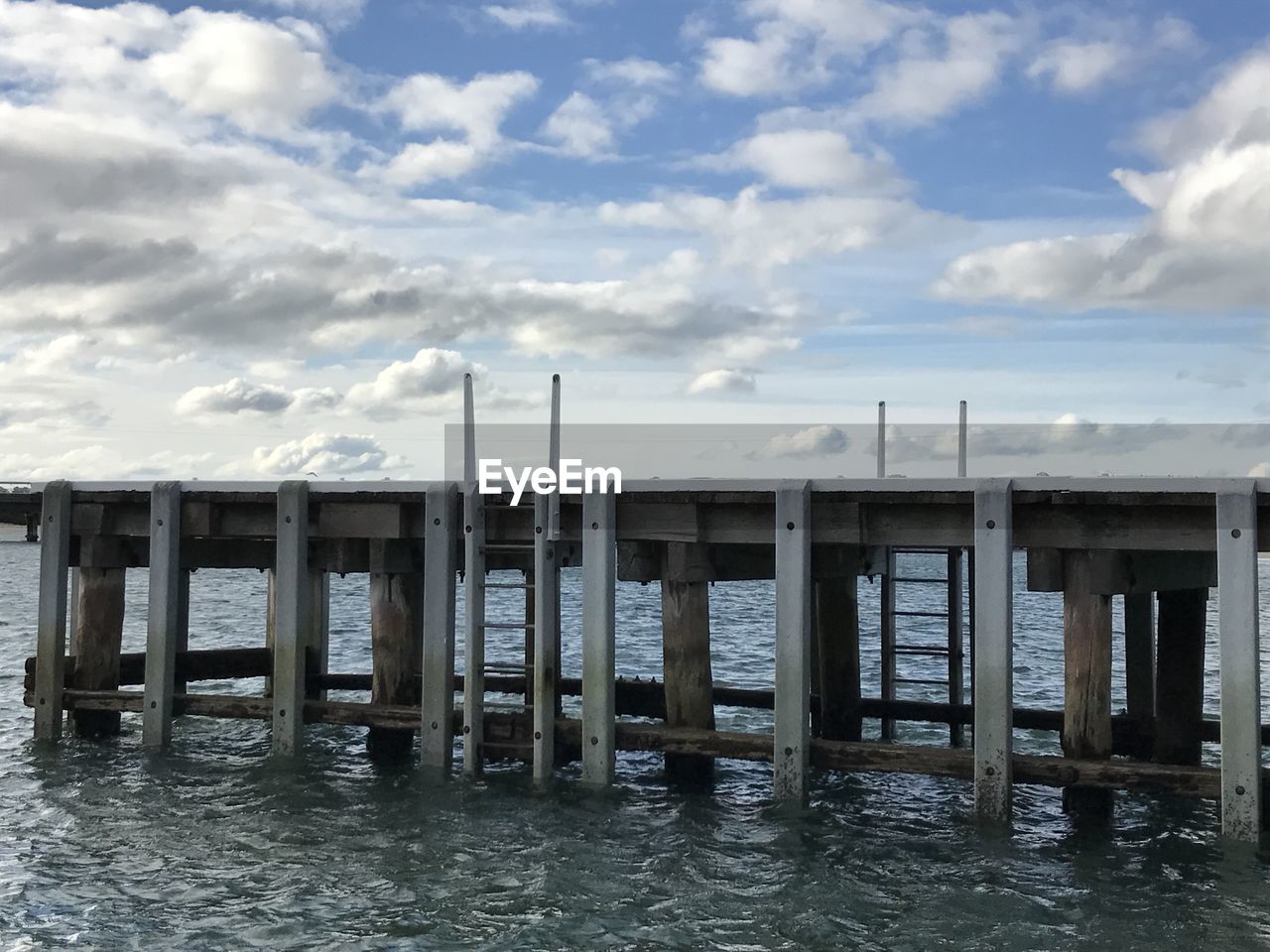 WOODEN POST ON BEACH AGAINST SKY