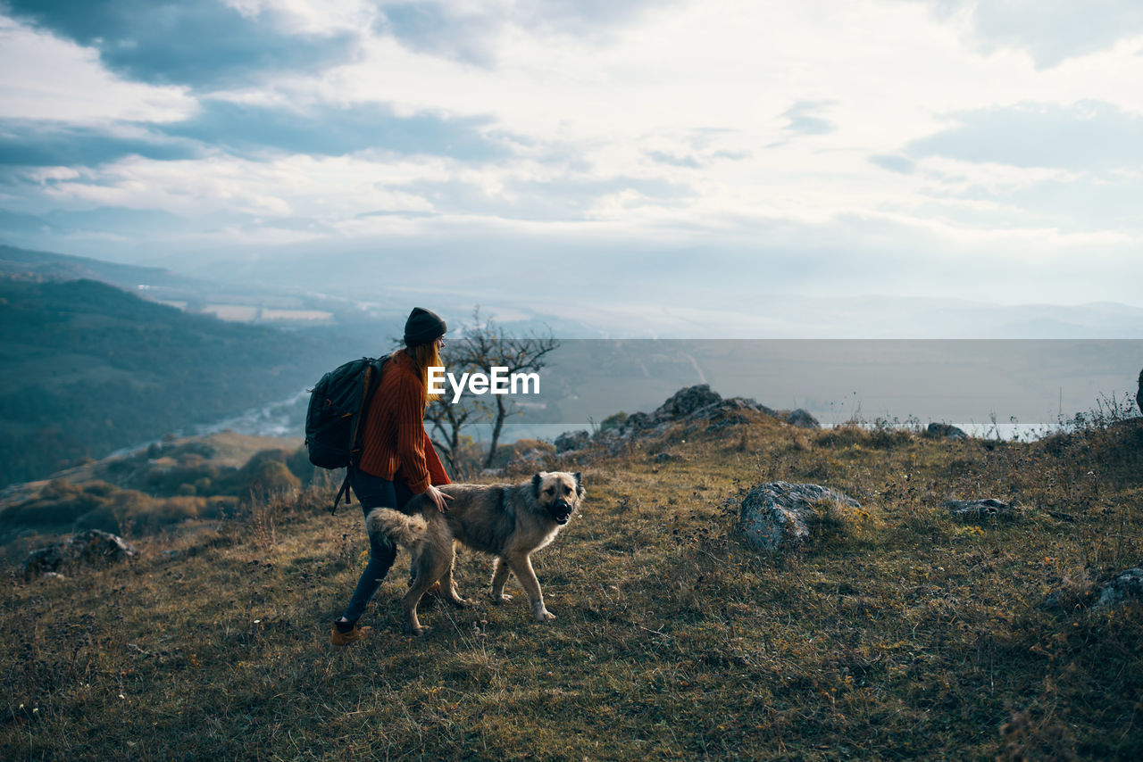 MAN WITH DOG ON MOUNTAIN AGAINST SKY