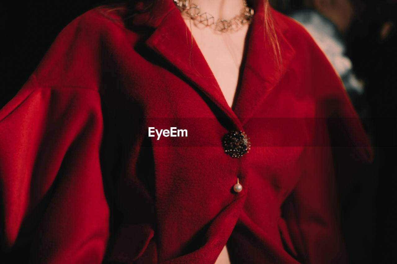 Part of a female body dressed in an elegant red jacket with golden buttons. women's  accessories