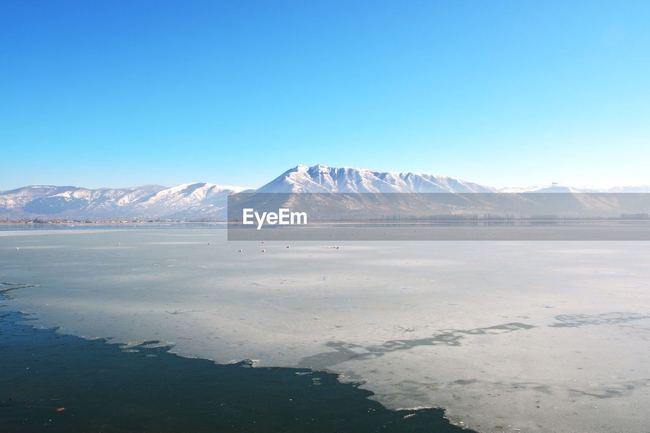 Winter landscape scene with frozen lake, snowy mountain