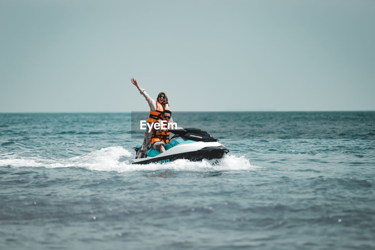 People in boat on sea against sky