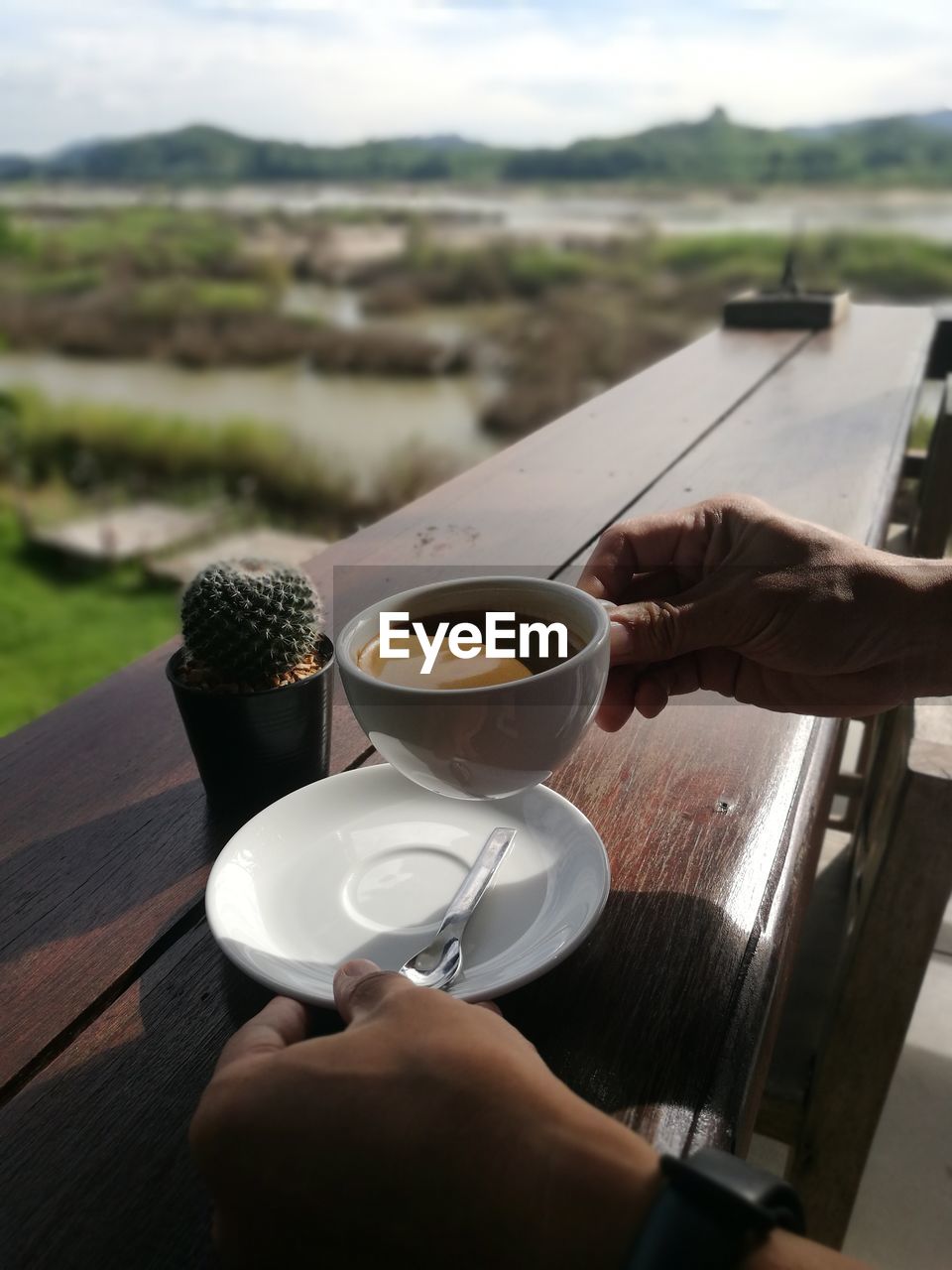 MAN HOLDING COFFEE CUP AND SPOON